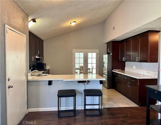 983 Orchard Ln, Colton, CA 92324 - kitchen with freestanding refrigerator, a peninsula, a kitchen breakfast bar, a textured ceiling, and dark brown cabinets