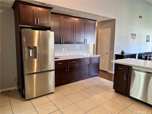 983 Orchard Ln, Colton, CA 92324 - kitchen with appliances with stainless steel finishes, light tile patterned flooring, dark brown cabinetry, decorative backsplash, and a textured ceiling