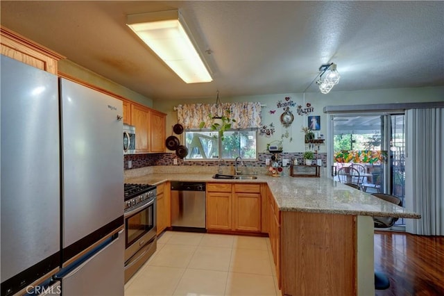 1808 Cave St, Redlands, CA 92374 - kitchen featuring stainless steel appliances, a peninsula, a kitchen bar, light stone countertops, and tasteful backsplash