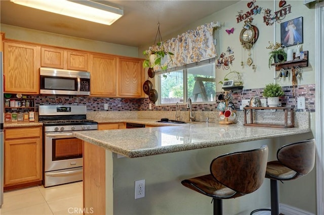 1808 Cave St, Redlands, CA 92374 - kitchen featuring stainless steel appliances, decorative backsplash, a peninsula, a breakfast bar area, and light tile patterned flooring