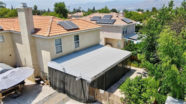 1808 Cave St, Redlands, CA 92374 - back of property with a chimney, solar panels, stucco siding, a tiled roof, and a mountain view