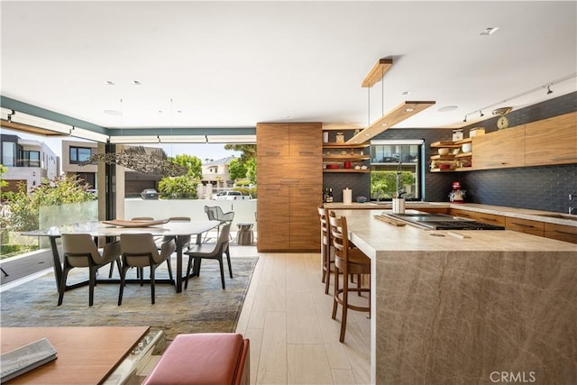 5429 E The Toledo, Long Beach, CA 90803 - kitchen with open shelves, stainless steel stovetop, tasteful backsplash, modern cabinets, and a center island