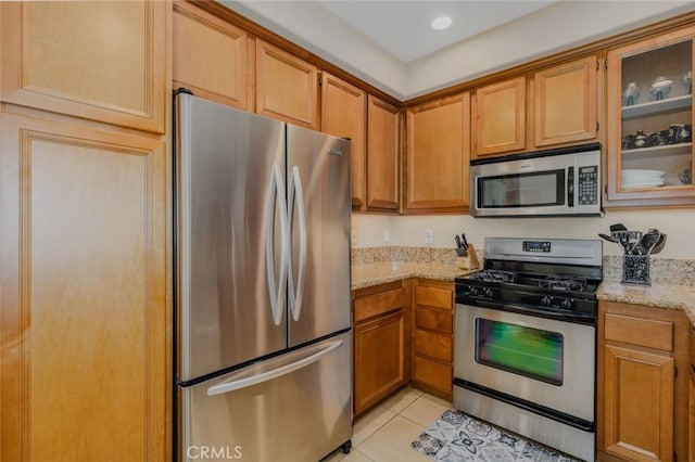8036 Picasso, Stanton, CA 90680 - kitchen featuring stainless steel appliances, light stone countertops, light tile patterned floors, glass insert cabinets, and brown cabinets