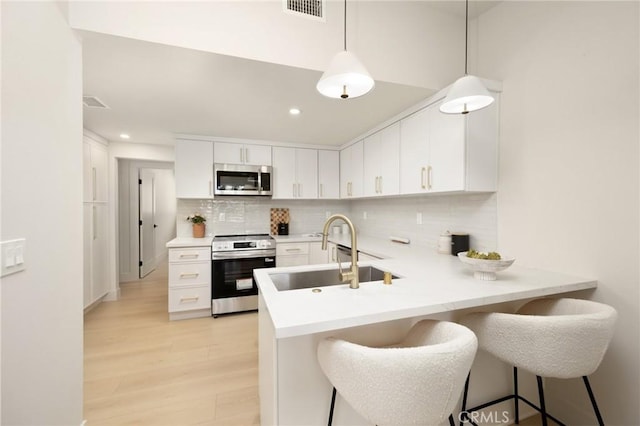 45 Oaktree Ln, Rolling Hills Estates, CA 90274 - kitchen featuring appliances with stainless steel finishes, tasteful backsplash, light wood finished floors, a peninsula, and white cabinets