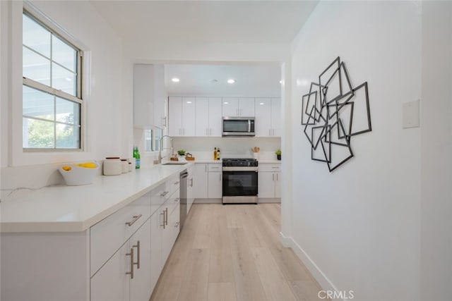 6535 Comanche Ave, Winnetka, CA 91306 - kitchen featuring appliances with stainless steel finishes, white cabinets, light wood-type flooring, recessed lighting, and light countertops