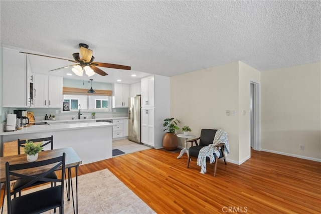 5160 Atherton Unit 73, Long Beach, CA 90815 - kitchen featuring appliances with stainless steel finishes, ceiling fan, a textured ceiling, light wood-type flooring, and a peninsula