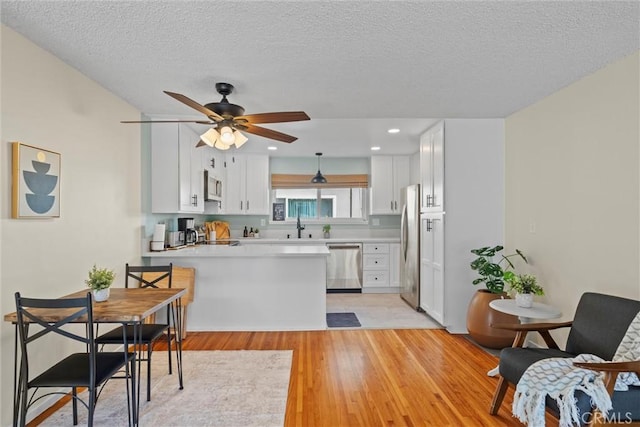 5160 Atherton Unit 73, Long Beach, CA 90815 - kitchen featuring stainless steel appliances, a peninsula, ceiling fan, white cabinets, and a textured ceiling