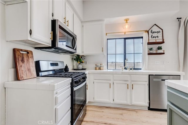 13432 Jubilee Pl, Victorville, CA 92395 - kitchen with stainless steel appliances, tile counters, and white cabinets