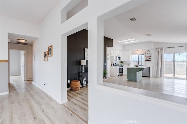 13432 Jubilee Pl, Victorville, CA 92395 - kitchen with appliances with stainless steel finishes, light wood finished floors, lofted ceiling, light countertops, and white cabinetry
