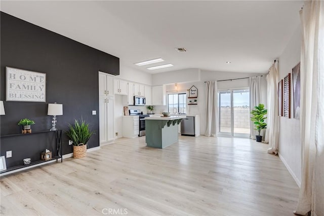 13432 Jubilee Pl, Victorville, CA 92395 - kitchen featuring appliances with stainless steel finishes, lofted ceiling, a kitchen island, white cabinets, and light wood-style floors