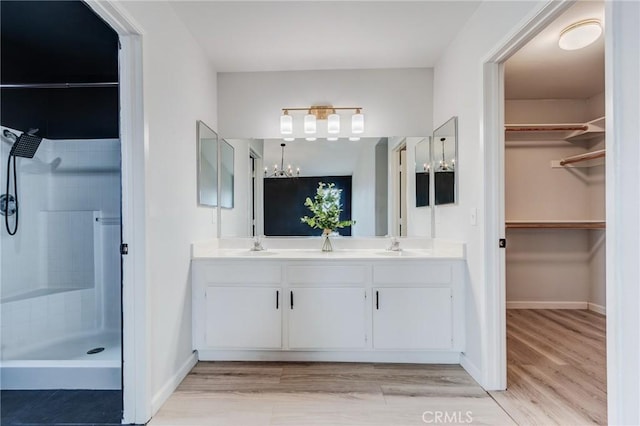 13432 Jubilee Pl, Victorville, CA 92395 - bathroom with double vanity, wood finished floors, a tile shower, a spacious closet, and a chandelier