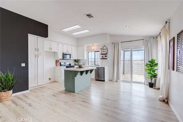 13432 Jubilee Pl, Victorville, CA 92395 - kitchen featuring appliances with stainless steel finishes, vaulted ceiling, light countertops, white cabinets, and a center island