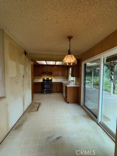 4773 Mount Rainier St, Jurupa Valley, CA 92509 - kitchen with black gas range oven, brown cabinets, under cabinet range hood, hanging light fixtures, and light flooring