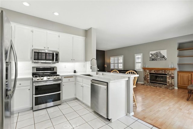 31397 Heitz Ln, Temecula, CA 92591 - kitchen featuring appliances with stainless steel finishes, a peninsula, open floor plan, light countertops, and decorative backsplash