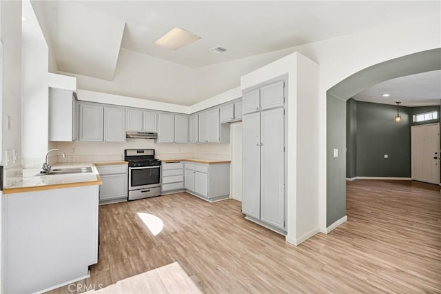1422 Deborah Pl, Beaumont, CA 92223 - kitchen with stainless steel gas range, gray cabinets, arched walkways, and under cabinet range hood