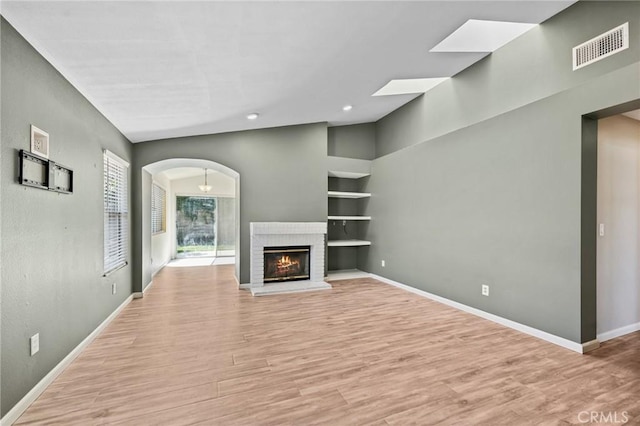1422 Deborah Pl, Beaumont, CA 92223 - unfurnished living room with built in features, light wood-style flooring, recessed lighting, a fireplace, and arched walkways