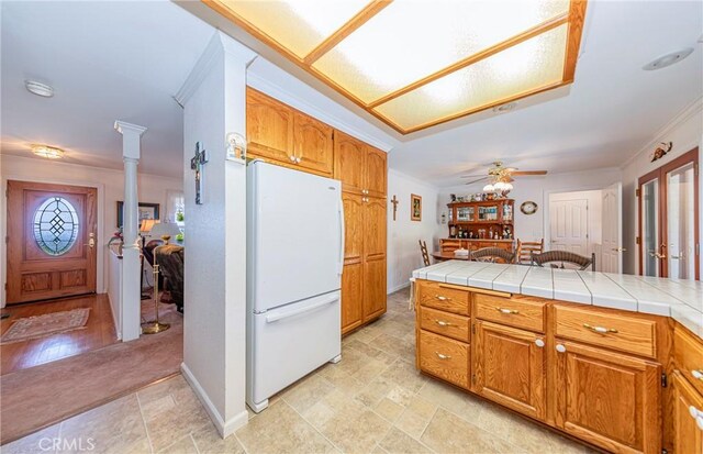 53235 Finegold Creek Ct, North Fork, CA 93643 - kitchen featuring freestanding refrigerator, ornamental molding, ornate columns, brown cabinetry, and tile countertops