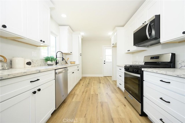903 E 7th St, Pomona, CA 91766 - kitchen with appliances with stainless steel finishes, light wood-type flooring, white cabinets, and light stone counters