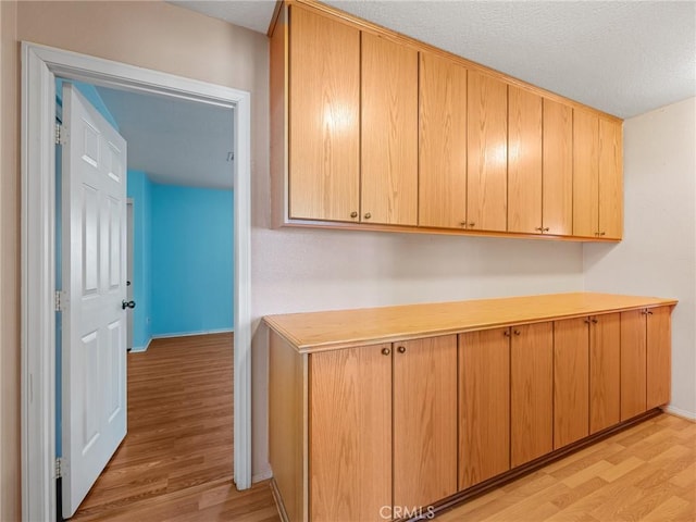 21756 Tussing Ranch Rd, Apple Valley, CA 92308 - kitchen with light wood-type flooring, light countertops, a textured ceiling, and light brown cabinetry
