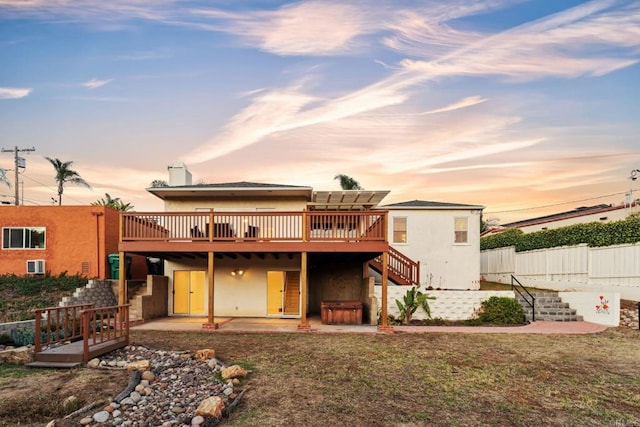 5038 Hastings Rd, San Diego, CA 92116 - back of property at dusk with a deck, stairs, stucco siding, a patio area, and a chimney