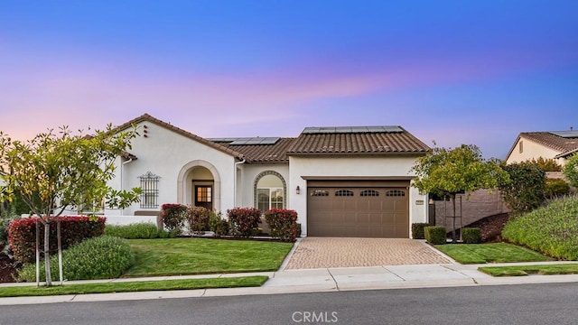 1849 Eucalyptus Rd, Nipomo, CA 93444 - mediterranean / spanish home featuring an attached garage, roof mounted solar panels, stucco siding, decorative driveway, and a front lawn
