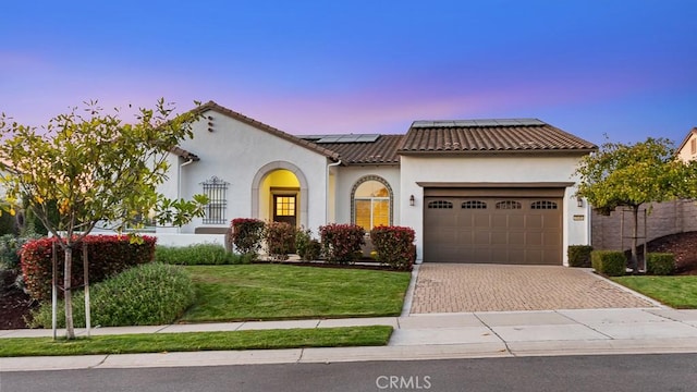 1849 Eucalyptus Rd, Nipomo, CA 93444 - mediterranean / spanish home featuring an attached garage, decorative driveway, roof mounted solar panels, stucco siding, and a front lawn
