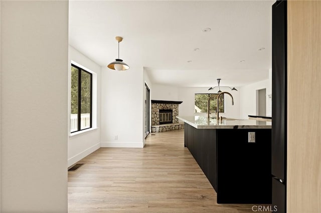 30260 Gremlin Ct, Running Springs, CA 92382 - kitchen featuring plenty of natural light, open floor plan, a stone fireplace, and light wood-style floors