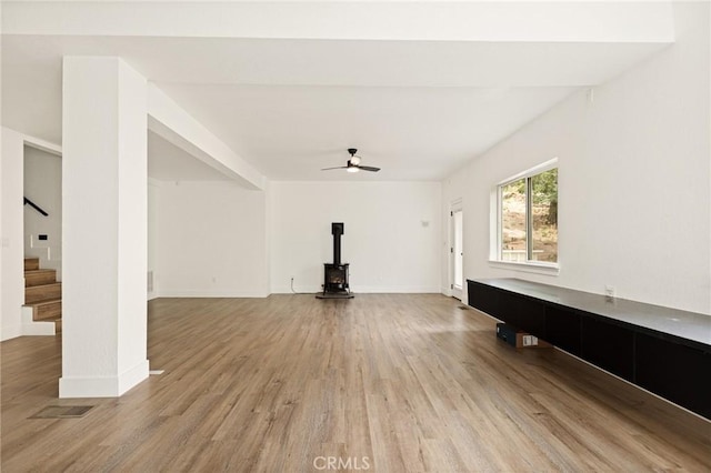 30260 Gremlin Ct, Running Springs, CA 92382 - unfurnished living room featuring light wood finished floors, a wood stove, stairs, and a ceiling fan