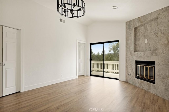 30260 Gremlin Ct, Running Springs, CA 92382 - unfurnished living room featuring wood finished floors, high vaulted ceiling, a chandelier, and a tile fireplace