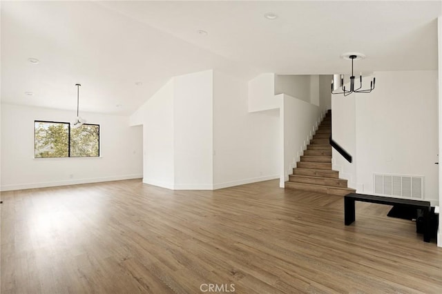30260 Gremlin Ct, Running Springs, CA 92382 - unfurnished living room with a chandelier, light wood-style flooring, and stairway