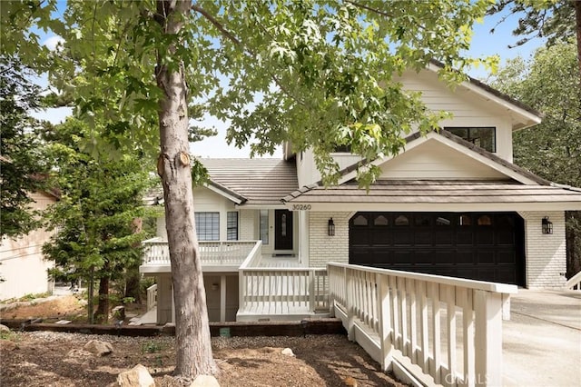 30260 Gremlin Ct, Running Springs, CA 92382 - view of front of property featuring brick siding, concrete driveway, an attached garage, a tile roof, and covered porch