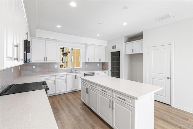 8608 Amherst St, Santee, CA 92071 - kitchen with white cabinets, light wood finished floors, backsplash, recessed lighting, and a kitchen island
