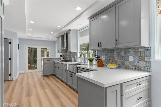 232 7th St, Seal Beach, CA 90740 - kitchen with gray cabinets, light countertops, backsplash, light wood-style flooring, and wall chimney range hood