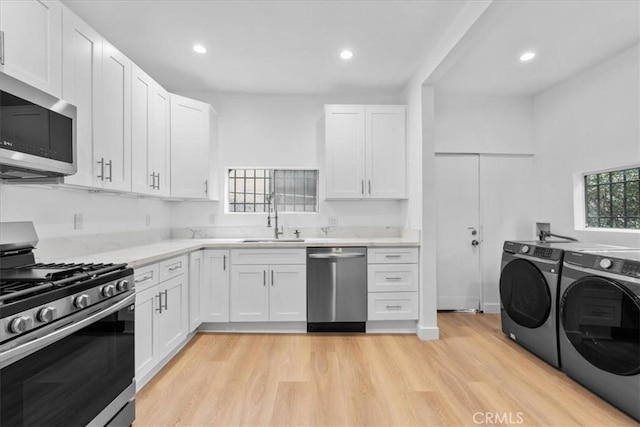 606 N Bonnie Brae St, Los Angeles, CA 90026 - kitchen with stainless steel appliances, washing machine and dryer, light wood-style flooring, white cabinets, and light countertops