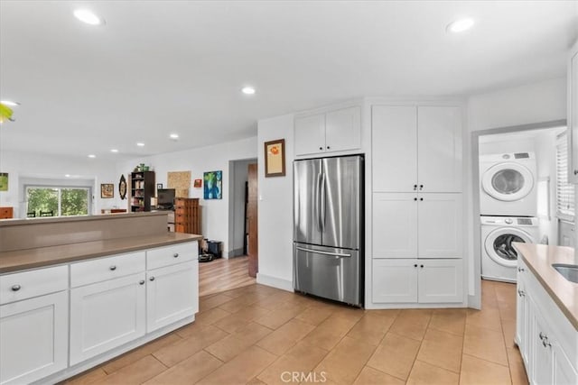 606 N Bonnie Brae St, Los Angeles, CA 90026 - kitchen with freestanding refrigerator, stacked washer / dryer, white cabinets, and recessed lighting