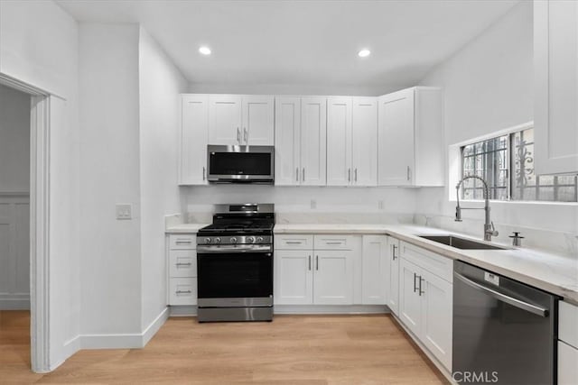 606 N Bonnie Brae St, Los Angeles, CA 90026 - kitchen featuring stainless steel appliances, white cabinetry, light wood finished floors, and recessed lighting