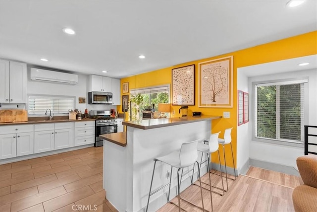 606 N Bonnie Brae St, Los Angeles, CA 90026 - kitchen with appliances with stainless steel finishes, an AC wall unit, white cabinets, plenty of natural light, and recessed lighting