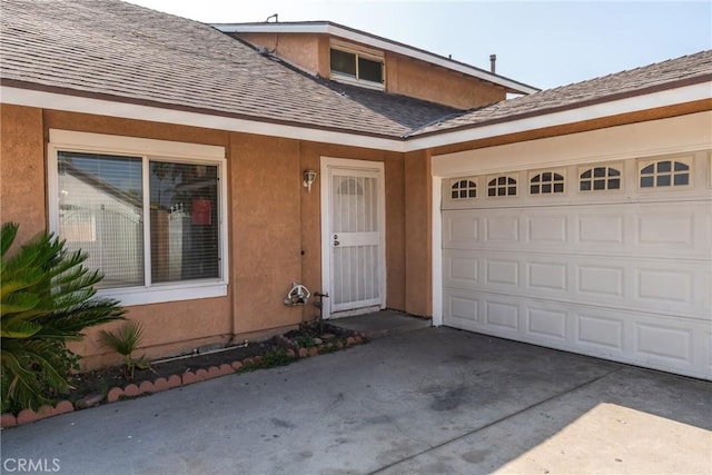 17571 Shamrock Ave, Fontana, CA 92336 - view of exterior entry featuring roof with shingles, driveway, an attached garage, and stucco siding