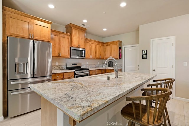 10 Harmony Park Cir, Chico, CA 95973 - kitchen featuring stainless steel appliances, recessed lighting, a kitchen bar, light stone countertops, and a center island with sink