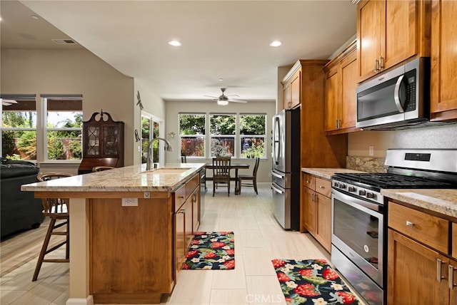 10 Harmony Park Cir, Chico, CA 95973 - kitchen featuring appliances with stainless steel finishes, a ceiling fan, a kitchen island with sink, brown cabinets, and recessed lighting