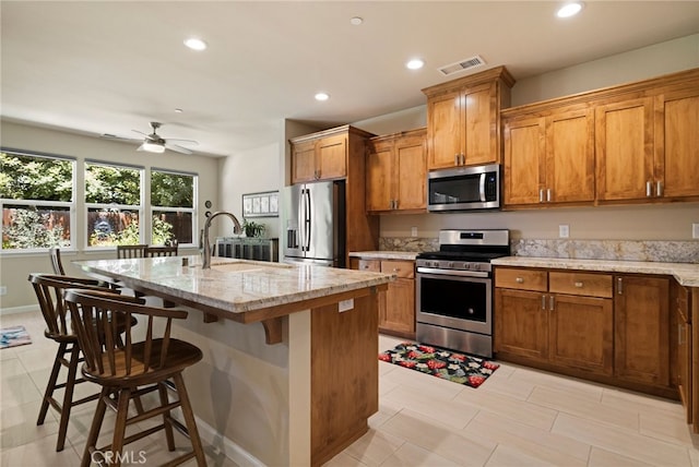 10 Harmony Park Cir, Chico, CA 95973 - kitchen featuring stainless steel appliances, recessed lighting, brown cabinets, a center island with sink, and light stone countertops