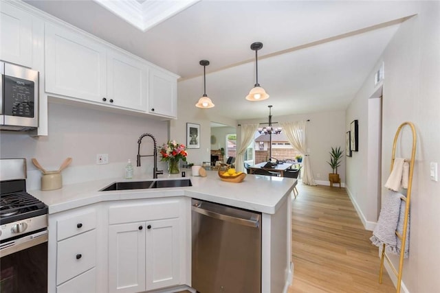 6313 Mockingbird St, Ventura, CA 93003 - kitchen featuring appliances with stainless steel finishes, a peninsula, a chandelier, light wood finished floors, and white cabinets