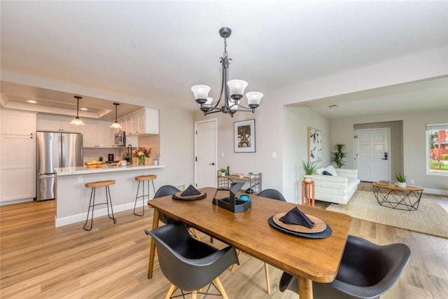 6313 Mockingbird St, Ventura, CA 93003 - dining space with light wood-type flooring, a chandelier, a raised ceiling, and recessed lighting