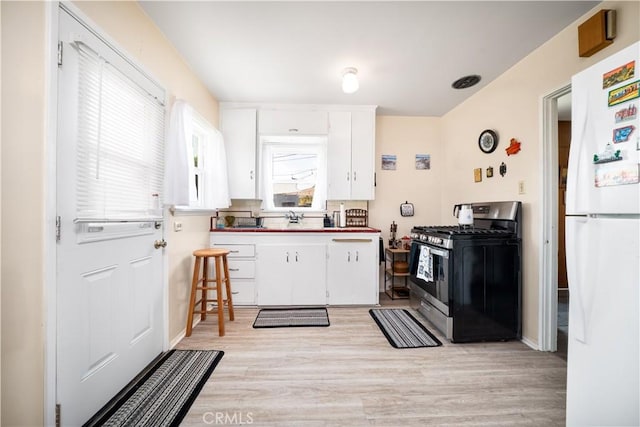 5870 Lemon Ave, Long Beach, CA 90805 - kitchen featuring stainless steel gas stove, freestanding refrigerator, light wood finished floors, and white cabinetry