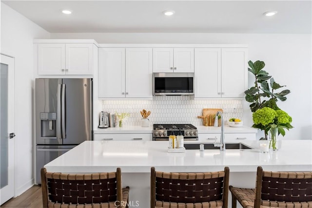 111 Juniper Dr, Rancho Mission Viejo, CA 92694 - kitchen with appliances with stainless steel finishes, light countertops, tasteful backsplash, white cabinets, and a breakfast bar