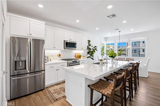 111 Juniper Dr, Rancho Mission Viejo, CA 92694 - kitchen with appliances with stainless steel finishes, backsplash, a breakfast bar, white cabinetry, and recessed lighting
