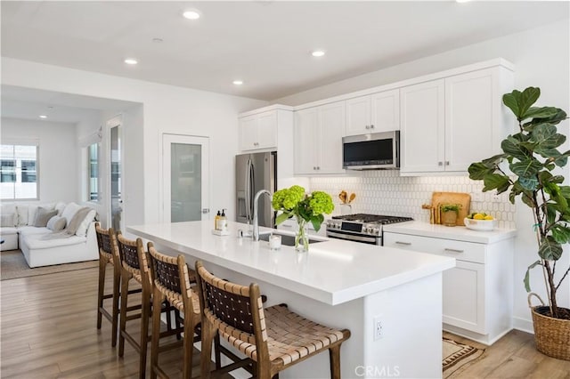 111 Juniper Dr, Rancho Mission Viejo, CA 92694 - kitchen featuring stainless steel appliances, a kitchen breakfast bar, tasteful backsplash, light wood-style flooring, and recessed lighting
