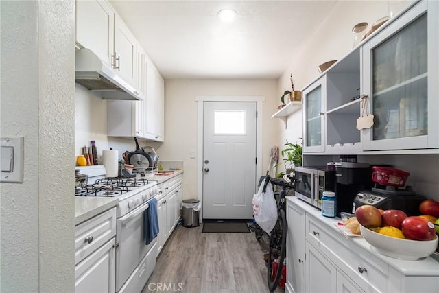 1335 W Burnett St, Long Beach, CA 90810 - kitchen with white gas stove, under cabinet range hood, light wood-style floors, light countertops, and white cabinets