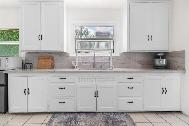 1335 W Burnett St, Long Beach, CA 90810 - kitchen featuring light tile patterned floors, white microwave, white cabinetry, and decorative backsplash
