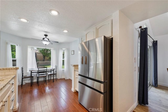 2578 Bryce Ct, Colton, CA 92324 - kitchen with freestanding refrigerator, a ceiling fan, white cabinets, dark wood-style flooring, and light stone counters